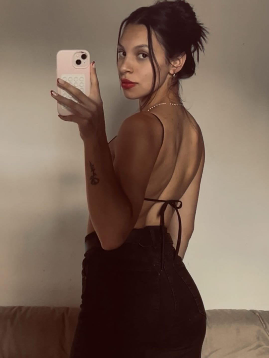 Woman in a black dress taking a mirror selfie in a quiet room